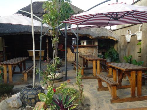 eine Terrasse mit Picknicktischen und einem Sonnenschirm in der Unterkunft Flintstones Backpackers in Lusaka