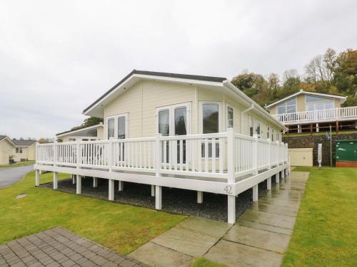 a white house with a porch and a yard at Cwtch Lodge 42 in Narberth