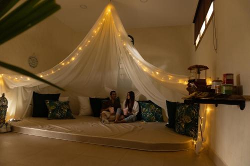 two people sitting on top of a bed in a room at Montana Glamping in Salento