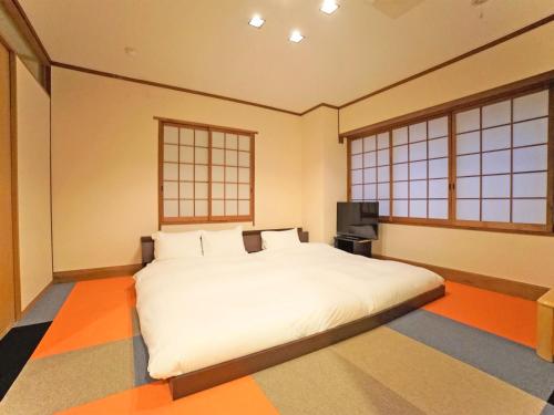 a bedroom with a large white bed and two windows at Hotel AreaOne Takamatsu in Takamatsu