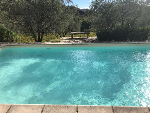 a pool of blue water with a bench in the background at Le Mas de Fanny in Faucon