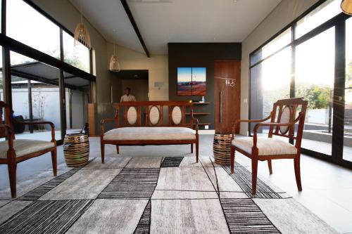 a living room with two chairs and windows at The Elegant Guesthouse in Windhoek