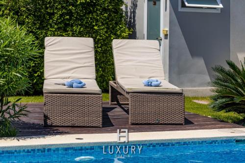 two wicker chairs sitting next to a swimming pool at Modern 3 Bedroom Private Pool Villa - MP67 in Hua Hin