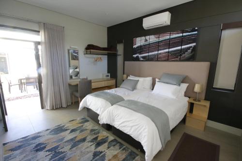 a bedroom with two beds and a desk in it at The Elegant Guesthouse in Windhoek
