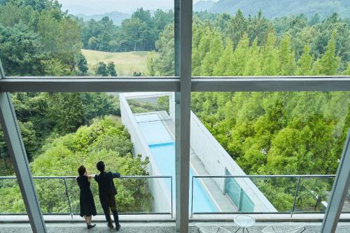 two people standing in a building looking at a swimming pool at SETOUCHI RETREAT by Onko Chishin in Matsuyama