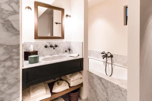 a bathroom with a sink and a tub and a mirror at 1898 The Post in Ghent