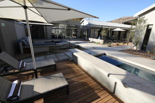 a patio with chairs and an umbrella and a pool at The Elegant Guesthouse in Windhoek