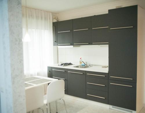 a kitchen with black cabinets and a sink and a table at Apartment FeLi House in Kyiv