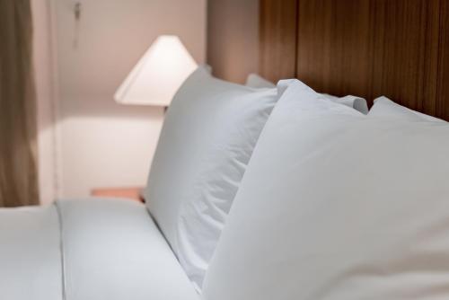a close up of two white pillows on a bed at Oriens Hotel & Residences Myeongdong in Seoul