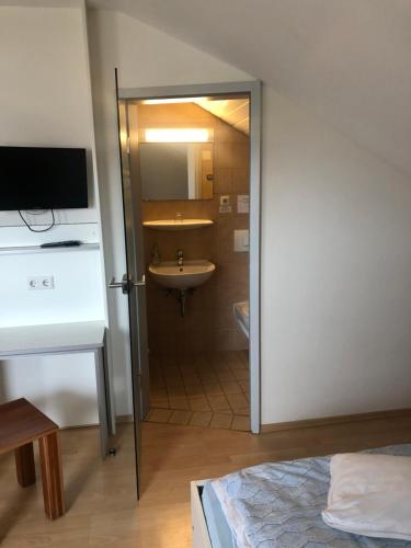 a bathroom with a sink and a door leading into a room at Landhaus Monika in Meckenbeuren