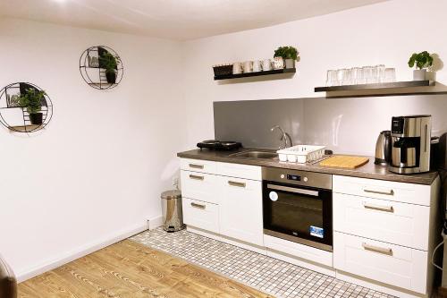 una cucina con armadi bianchi e forno nero di Work & longstay apartment Ingolstadt a Adelschlag