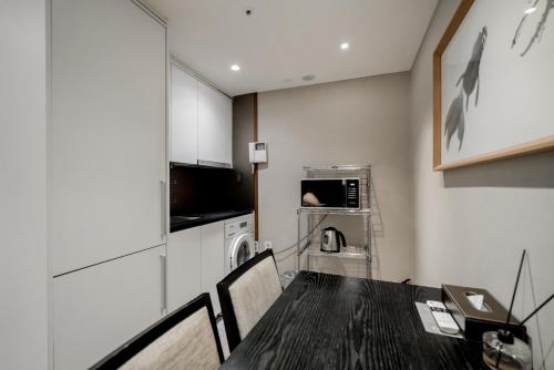 a dining room with a table and a kitchen at Oriens Hotel & Residences Myeongdong in Seoul