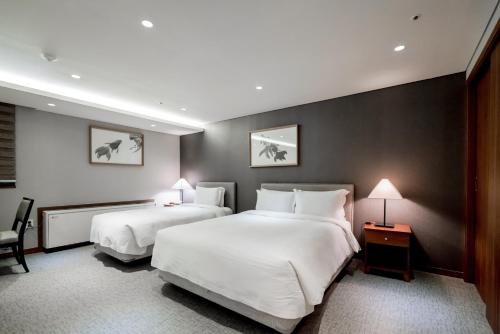 a hotel room with two beds and a chair at Oriens Hotel & Residences Myeongdong in Seoul