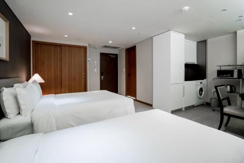 a hotel room with a white bed and a television at Oriens Hotel & Residences Myeongdong in Seoul