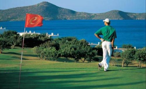 a man standing on a golf course with a red flag at Villa Estée, luxury villa with private infinity pool and jacuzzi in Elounda