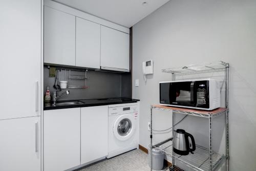 a kitchen with a microwave and a washing machine at Oriens Hotel & Residences Myeongdong in Seoul