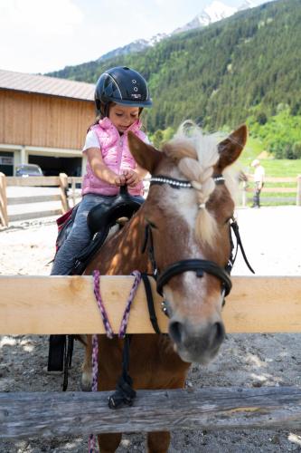 a little girl is sitting on a horse at Familotel Kindl in Neustift im Stubaital