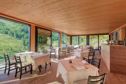 un restaurante con mesas, sillas y ventanas grandes en Re Delle Alpi Resort & Spa, 4 Stelle Superior, en La Thuile