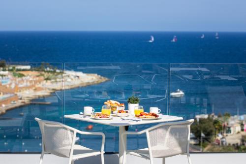 a table with plates of food and a view of the ocean at be.HOTEL in St. Julianʼs