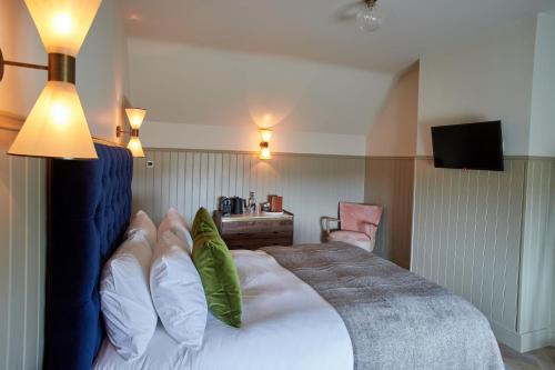 ein Hotelzimmer mit einem Bett mit grünen Kissen in der Unterkunft The Ingham Swan in Stalham