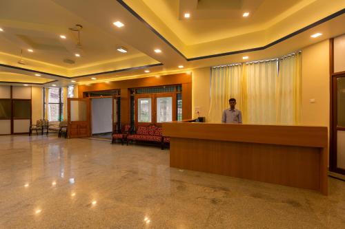 a man standing at a reception desk in a lobby at KSTDC Hotel Mayura Krishna Almatti in Bāgalkot