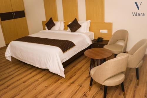 a hotel room with a bed and a table and chairs at Hotel Vdara in Vijayawāda