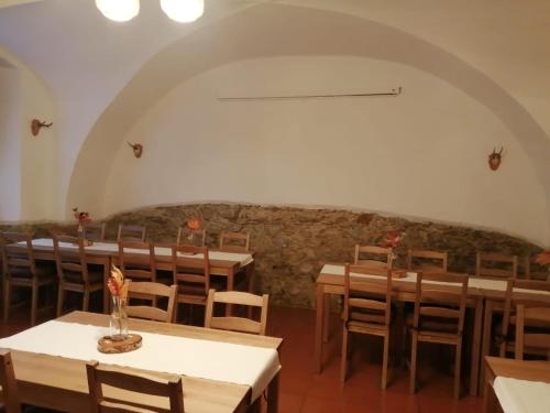 a room with tables and chairs and a stone wall at Penzion U Šlechtičen in Milovy