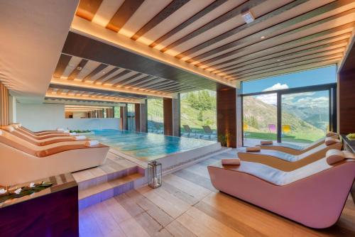 a living room with a swimming pool and two couches at Re Delle Alpi Resort & Spa, 4 Stelle Superior in La Thuile