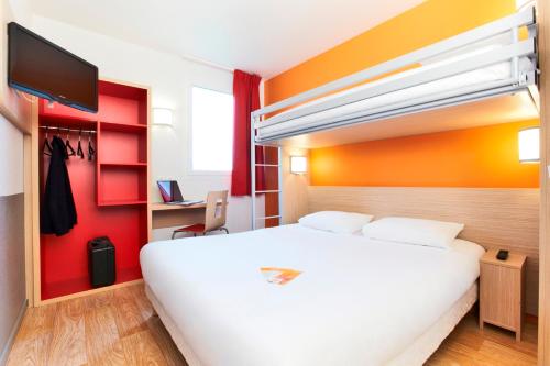 a hotel room with a white bed and a flat screen tv at Premiere Classe Caen Nord - Mémorial in Caen