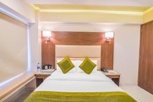 a hotel room with a bed with yellow and green pillows at Oxford Powai in Mumbai