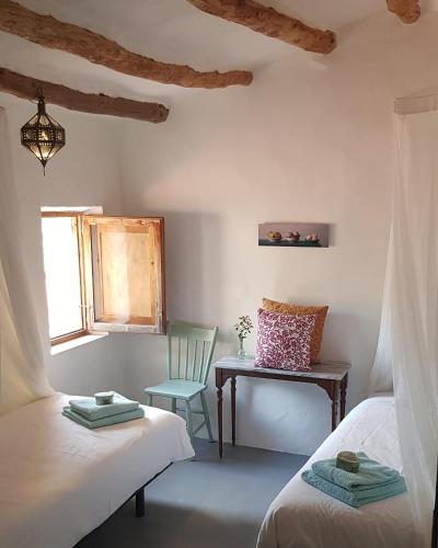 a room with two beds and a table and a chair at Mas de Mingall in Les tres Cales