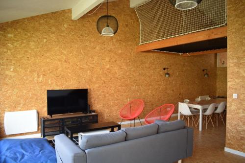 a living room with a couch and a tv and a table at Gîte Esprit loft in Macau