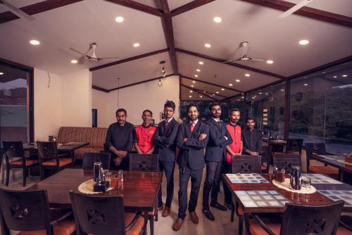 un grupo de hombres parados en una habitación con mesas en La Serene Resort and Spa en Mahabaleshwar