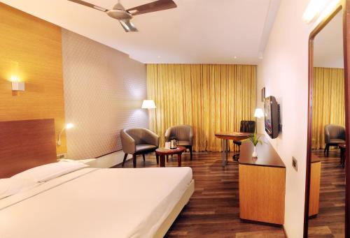 a hotel room with a bed and a table and chairs at Hotel Indraprastha in Palakkad