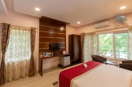 a bedroom with a bed and a tv and a window at KSTDC Hotel Mayura Riverview Srirangapatna in Seringapatam