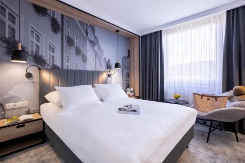 a bedroom with a large white bed and a chair at Mercure Jelenia Góra in Jelenia Góra