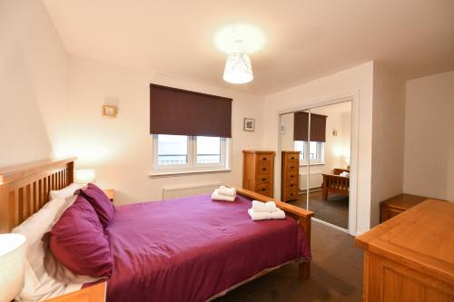 歐文的住宿－Harbour Quay Apartment，一间卧室配有一张带紫色床单的大床