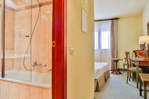 a hotel room with a bathroom with a tub and a bedroom at Velada Mérida in Merida
