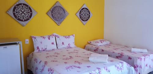 a bedroom with two beds and a yellow wall at Pousada Água Viva in Ilha de Boipeba