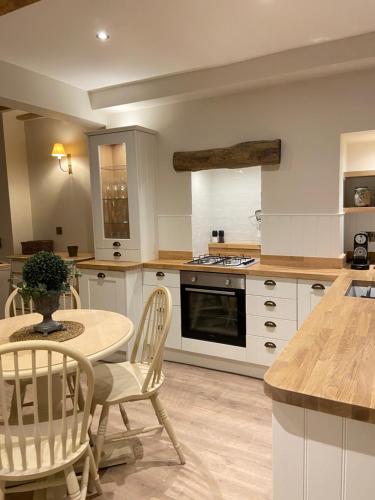 a kitchen with white cabinets and a table and chairs at Bailey Cottage in Gargrave