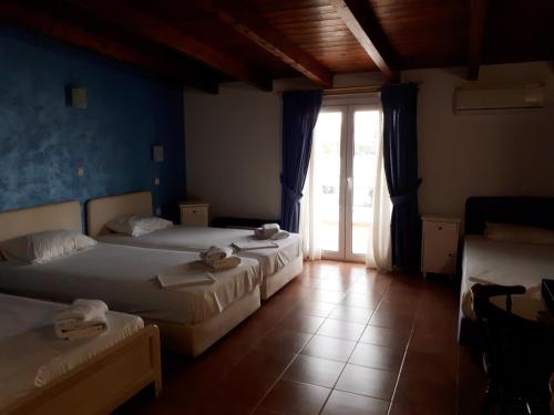 een slaapkamer met 2 bedden en een deur naar een patio bij Hotel Scala in Paralía Rachón