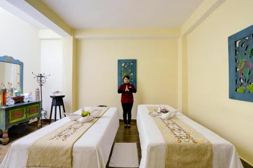 a woman standing between two beds in a room at The Fern Denzong Hotel & Spa Gangtok, Sikkim in Gangtok