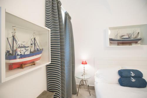 een slaapkamer met een bed en een gordijn met een boot bij Hotel Marina Charming Rooms in Finale Ligure