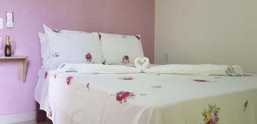 a white bed with white sheets and flowers on it at Pousada Água Viva in Ilha de Boipeba