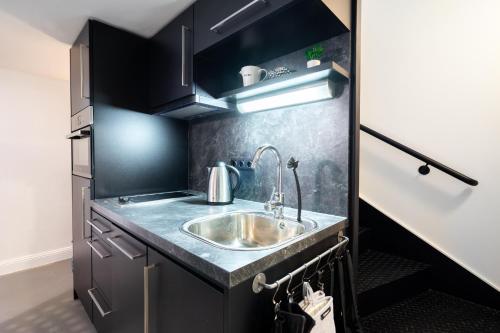 eine Küche mit einem Waschbecken und schwarzen Schränken in der Unterkunft The Music - Luxuriöses City Loft am Naschmarkt in Wien