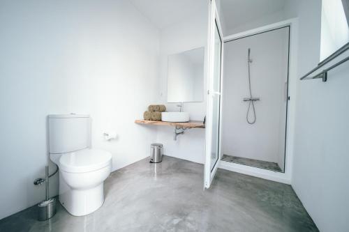 a white bathroom with a toilet and a shower at Retiro Atlântico in Urzelina