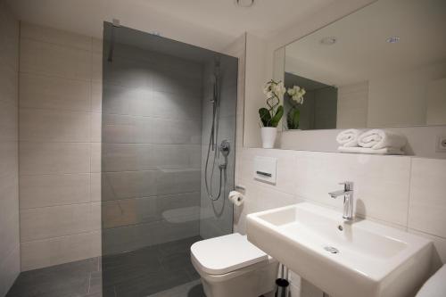 a bathroom with a shower and a toilet and a sink at Leo Apartments Miesbach in Miesbach