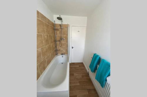 a bathroom with a white tub and blue towels at Bank Street Apartment in Herne Bay