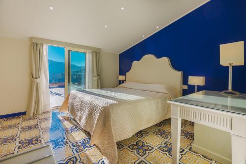 ein blaues Schlafzimmer mit einem Bett und einem Tisch in der Unterkunft Hotel La Vue d'Or in Sorrent