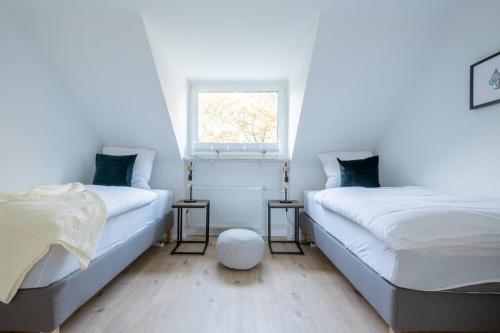 two beds in a white room with a window at cruwzo I Apartments am Uniklinikum in Essen